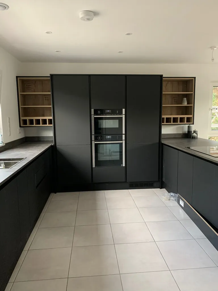 Matt black kitchen with tall oven housing and open shelf units