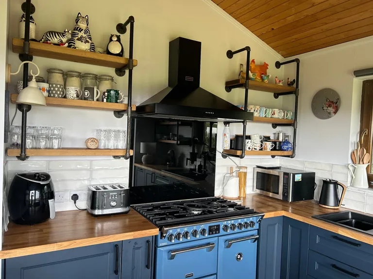 Blue shaker kitchen with range cooker, oak worktops and pipe shelving