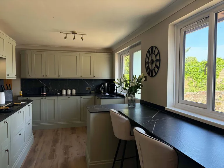 Sage shaker kitchen with a breakfast bar under the window